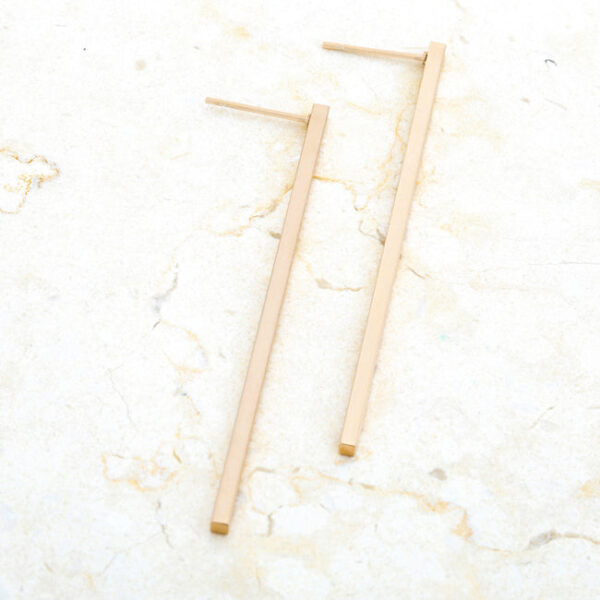 Angled view of the goldtone earrings showing the metal's plated surface sheen