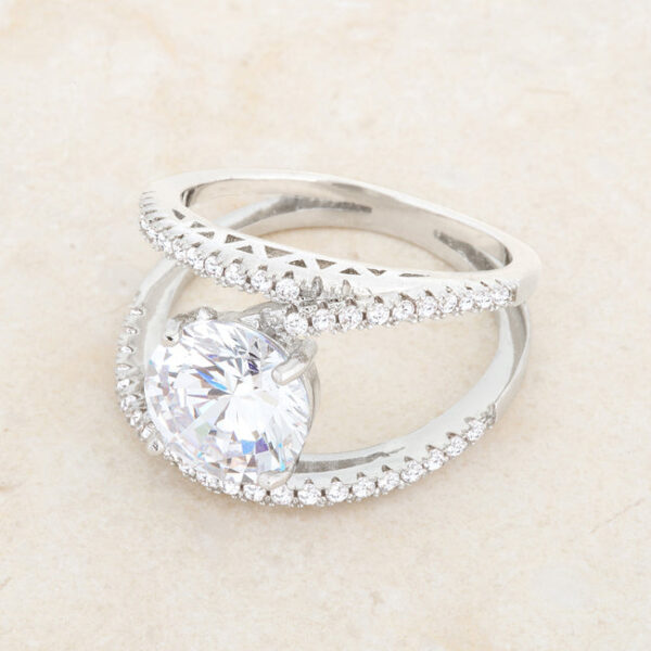 Rhodium plated clear cubic zirconia ring laid flat on a plain background