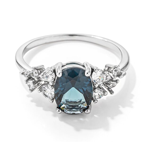 Ring with an oval blue green cubic zirconia center stone on a rhodium plated band