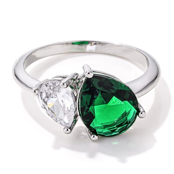Toi et moi ring with a clear and a green pear cut cubic zirconia set side by side on a rhodium plated band