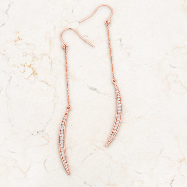 Pair of rose goldtone moon drop earrings laid side by side showing matching pave stone setting