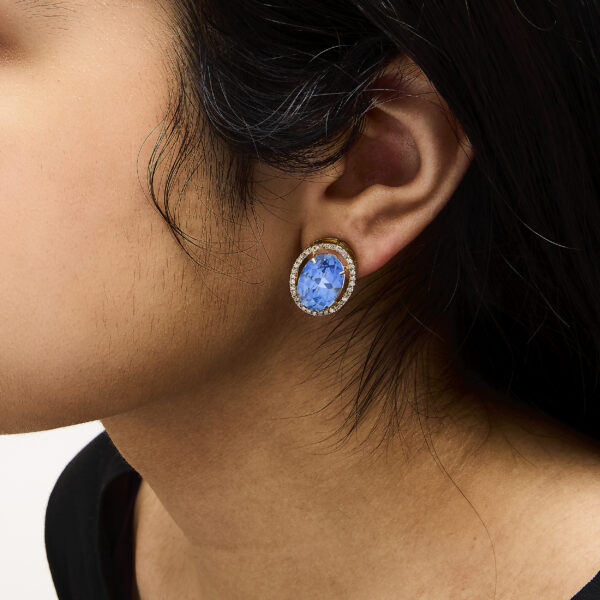 Blue fluorite oval diamond halo stud earrings worn on a model's ear