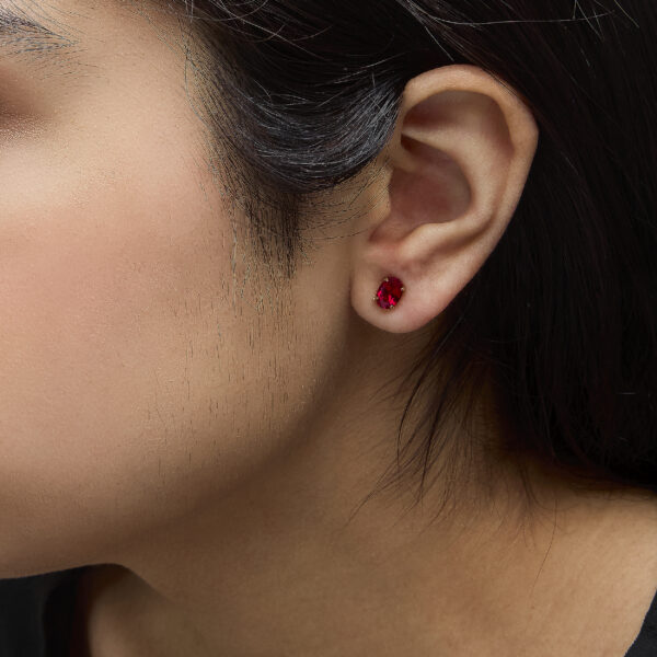 18K yellow gold ruby stud earrings shown worn in an ear