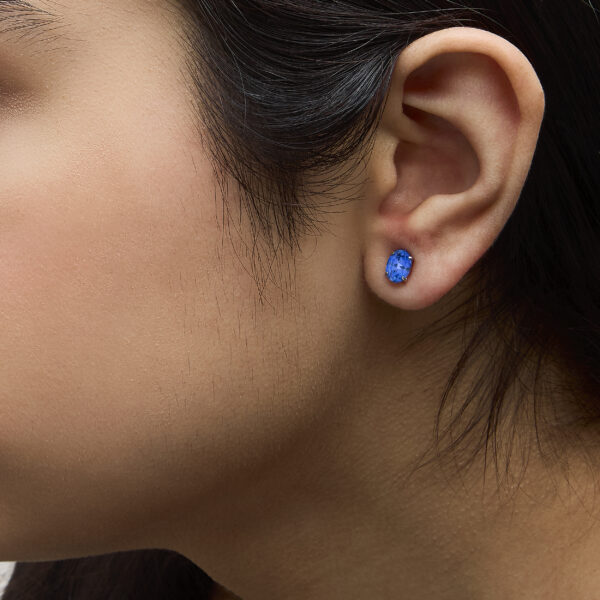 Model wearing platinum oval blue sapphire stud earrings on the ear