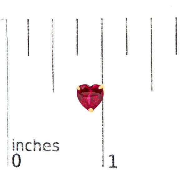 Ruby heart stud earrings shown next to a scale reference for size comparison