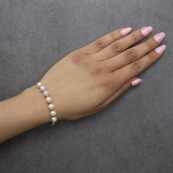 Gold pearl cuff bangle bracelet worn on a model's wrist