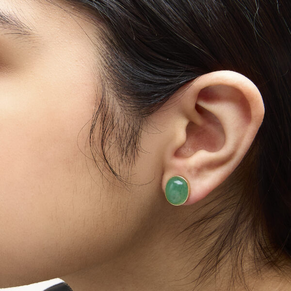 Green aventurine stud earrings worn on an ear