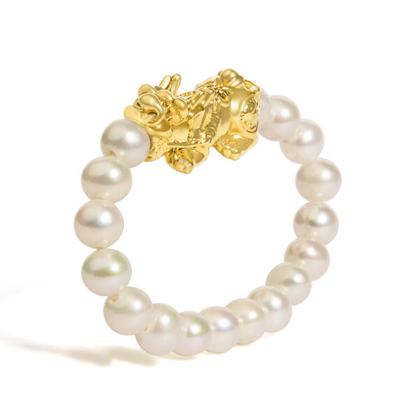 Side angle of the gold dragon ring showing the pearl band curving around the finger